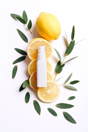 Cream bottle and lemon slices with green leaves on white backgroundの写真素材