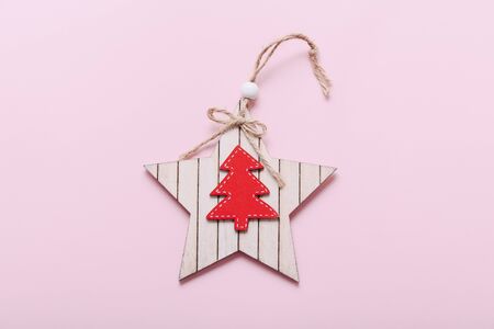 Christmas tree wooden toy in shape of star with Christmas tree figure on pink backgroundの写真素材