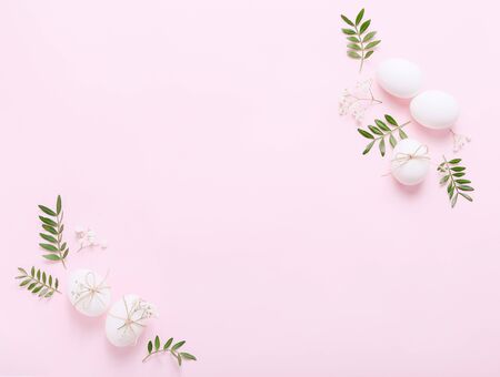 White Easter eggs with flowers and green leaves on pink backgroundの写真素材