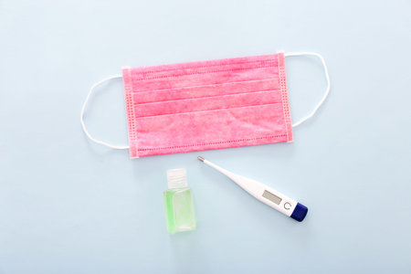 Medical mask, Medical protective mask with a thermometer, and hand sanitizer on blue background....