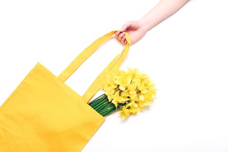 Spring narcissus flowers in yellow bag on white background. Top viewの写真素材