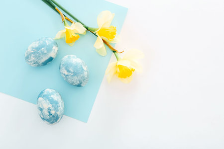 Happy Easter background. Easter eggs with spring flowers on white background, top view
