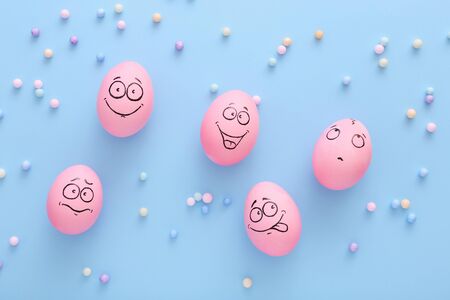 Funny pink eggs with face feeling on blue backgroundの写真素材