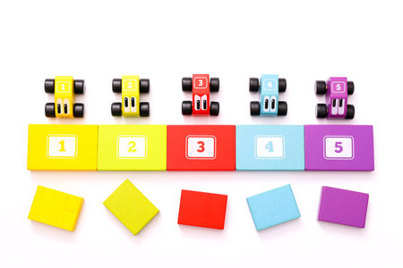 Educational toys for kids. Colorful wooden cars with numbers on white background. Top view