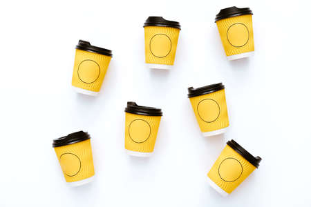 Many yellow cups of coffee takeaway, paper cups on white background. Flat lay style. Top view.の写真素材