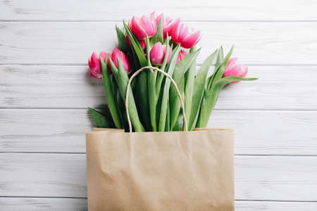 Shopping craft bag with pink tulips on white wooden background. Zero waste conceptの写真素材