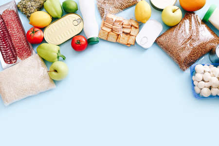Set of grocery items from canned food, vegetables, cereal on blue background. Food delivery concept. Donation concept. Top view.の写真素材