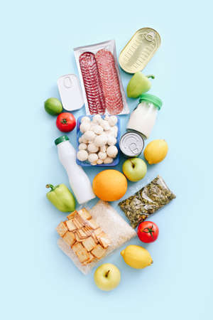 Set of grocery items from canned food, vegetables, cereal on blue background. Food delivery concept. Donation concept. Top view.の写真素材