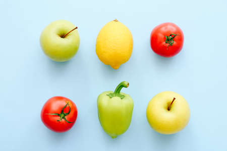 Various fresh vegetables and fruits on blue background. Shopping concept. Tomato, pepper, lemon, apple in row. Top viewの写真素材