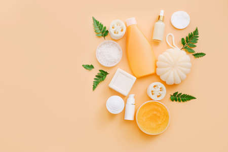 Bath accessories and natural cosmetics with green leaves on peach color background, top viewの写真素材