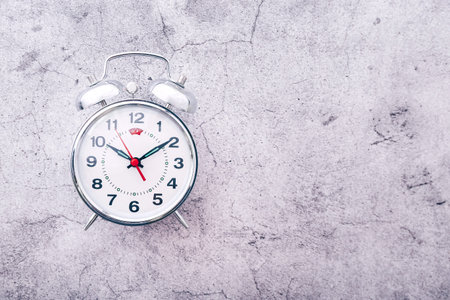 Silver alarm clock on cement background. Top view. Copy space