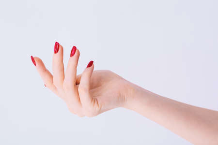 Female hand with red manicure on light grey backgroundの写真素材