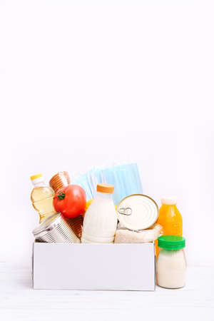 Donation box with food supplies for the period of quarantine on white background. Set of grocery items from canned food, vegetables, cereal. Food delivery concept.の写真素材