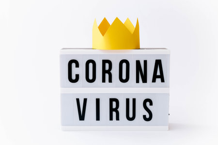 Covid 19, Corona virus text on display in lightbox with crown on it, light background.の写真素材