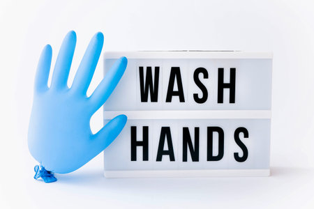 Wash your hands. Text on lightbox display with blue glove balloon on light background.