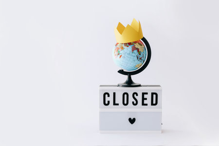 Concept of lock down,   Text on display in lightbox and globe with crown on it, light background.の写真素材