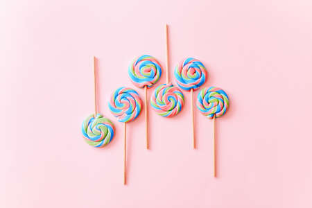 Colorful lollipops swirls on sticks. Striped spiral multicolored candy on pink background, top viewの写真素材