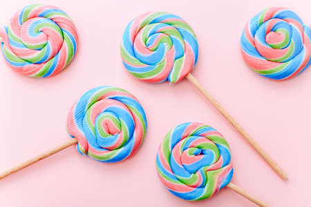 Colorful lollipops swirls on sticks. Striped spiral multicolored candy on pink background, top viewの写真素材