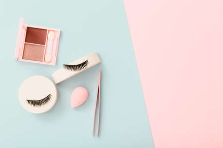 Flat lay composition with products for decorative makeup on pastel blue and pink backgroundの写真素材