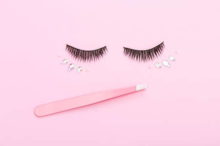 False eyelashes and tweezers on pink background. Layout of the beauty industry. Beauty and fashion.の写真素材