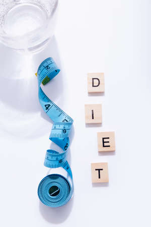 Glass of water and a measuring tape with word Diet on white backgroundの写真素材