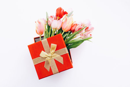 Gift box with bouquet of beautiful tulips on white background, top viewの写真素材