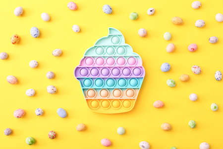 Trendy toy antistress, pop it on a yellow background, fidget toy with candies, top viewの写真素材