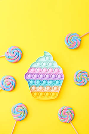 Trendy toy antistress, pop it on a yellow background, fidget toy with candies, top viewの写真素材