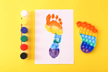 New trendy popular silicone colorful anti stress  toy for child and colorful footprint on yellow background.の写真素材