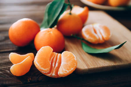 Fresh clementines with leaves on wooden table, close upの写真素材