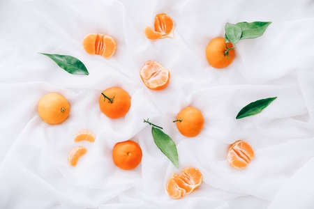 Fresh clementines with leaves on white fabric, top viewの写真素材