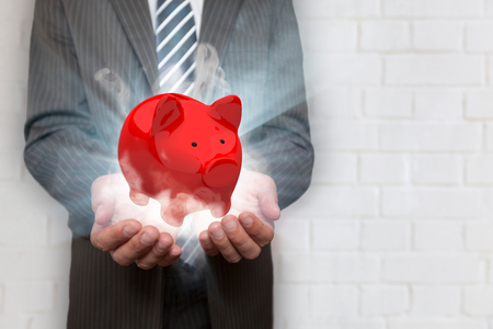 Businessman with red piggy bank, rays and smoke. の写真素材