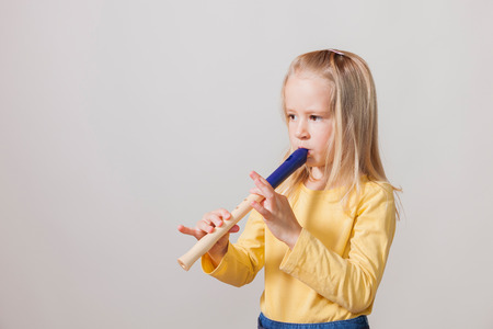 Blond hair girl with flute on the bright background.の写真素材