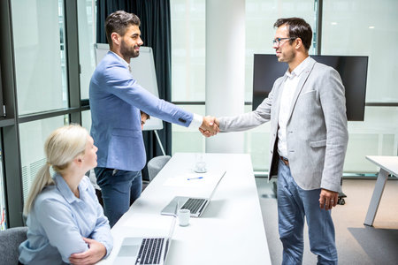 Business people greet each other at a meeting with a handshake.