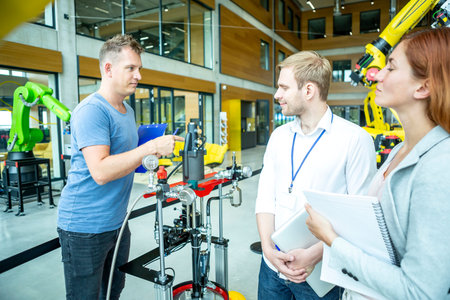 Engineers inspect industrial robot in a hall.