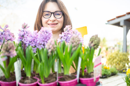 A mature woman gardener cares for the flowering plants in the nursery.の写真素材