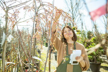 A mature woman gardener in a nursery among the trees.の写真素材