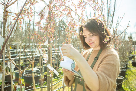 A mature woman gardener in a nursery among the trees.の写真素材