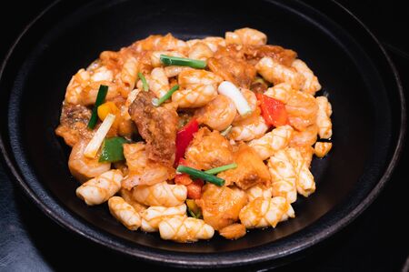 Stir fried squid with salted egg on a black dishの写真素材