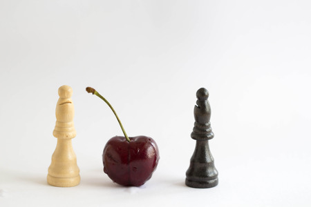 cherry on center of black and white chess on white backgroundの写真素材