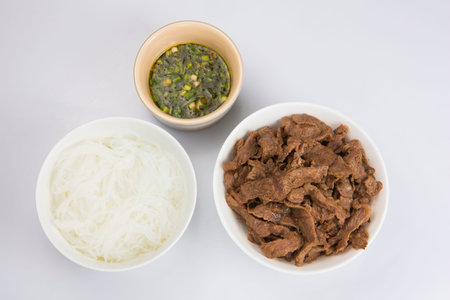 isolated close up flat lay top view shot of a bowl of sliced beef fillet pieces, a plate of...