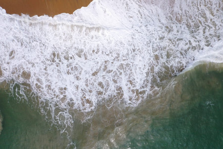 aerial drone bird view shot of the sea surface with turquoise blue water, large white waves, foam...