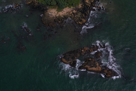 aerial drone bird view shot of the sea surface with turquoise blue water, a small island, brown...