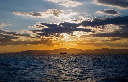 dramatic panorama seascape shot of a lonely tanker silhouette in wavy blue ocean at a beautiful...