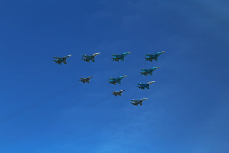a triangular formation of a group of ten russian military fighter jet planes flying high in blue sky...