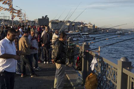 ISTANBUL / TURKEY - 30/05/2015: a regular daily gathering of a large crowd of turkish male fishermen for favorite hobby evening sunset fishing with their lanes in the Bosporus from Galata Bridgeの写真素材
