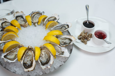 top view close up filled frame food shot of fresh raw shucked open oysters lying between lemon...