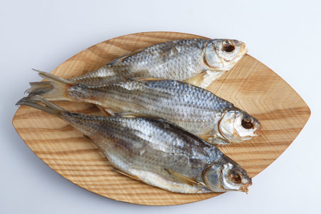 isolated close up top view shot of three Russian dried salted vobla (Caspian Roach) fish on a wooden...