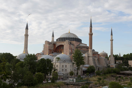 Beautiful close up day shot of the Hagia Sophia Museum (old orhodox Cathedral and Ottoman imperial Mosque) with its large circular dome, four minarets and golden spikes on a cloudy light blue skyのeditorial素材