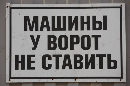 a close up shot of a black warning sign on a white background saying in Cyrillic russian DO NOT PARK CARS IN FRONT OF THE GATESの写真素材